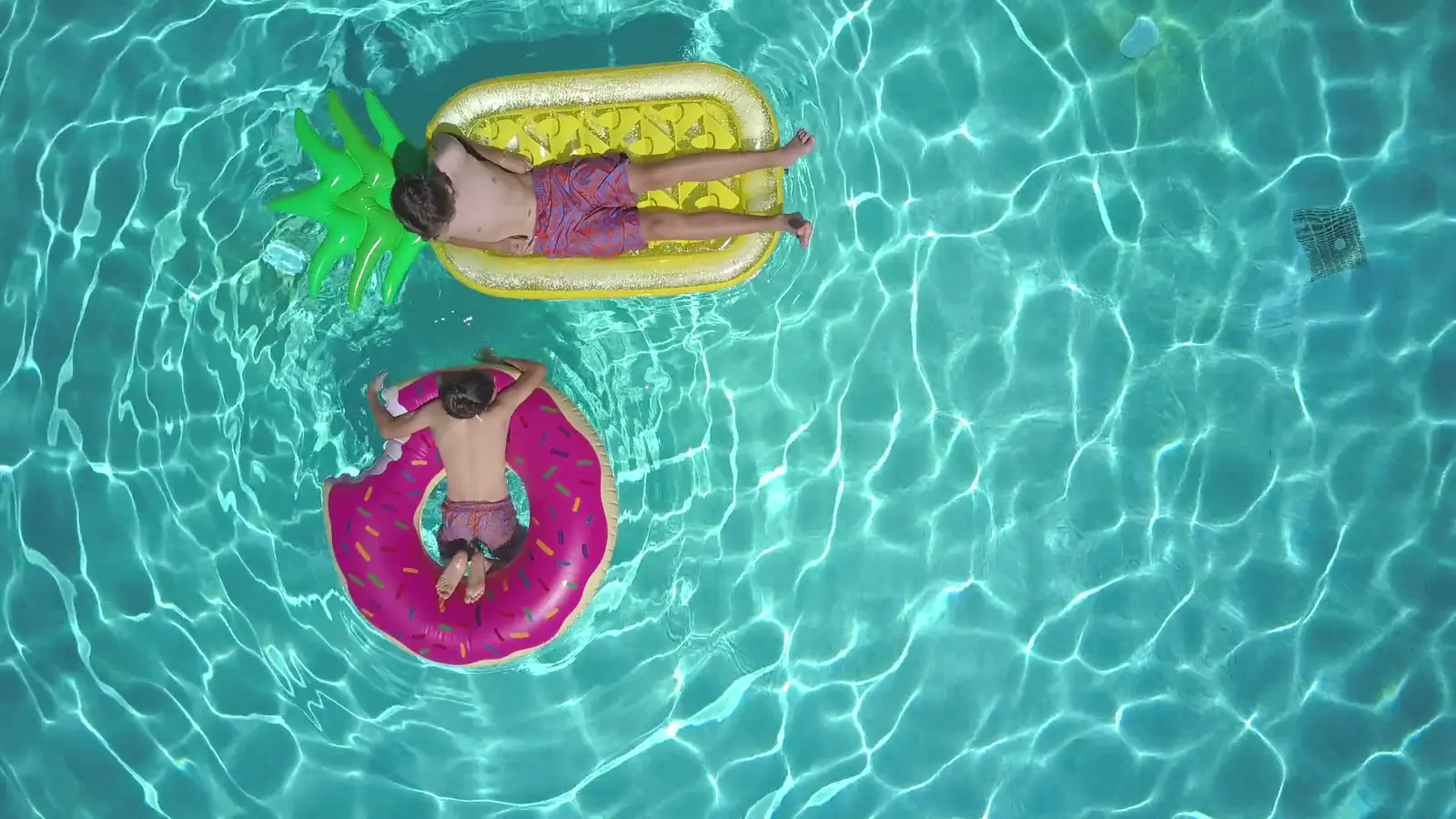 Chicos flotando en inflables en una piscina turquesa