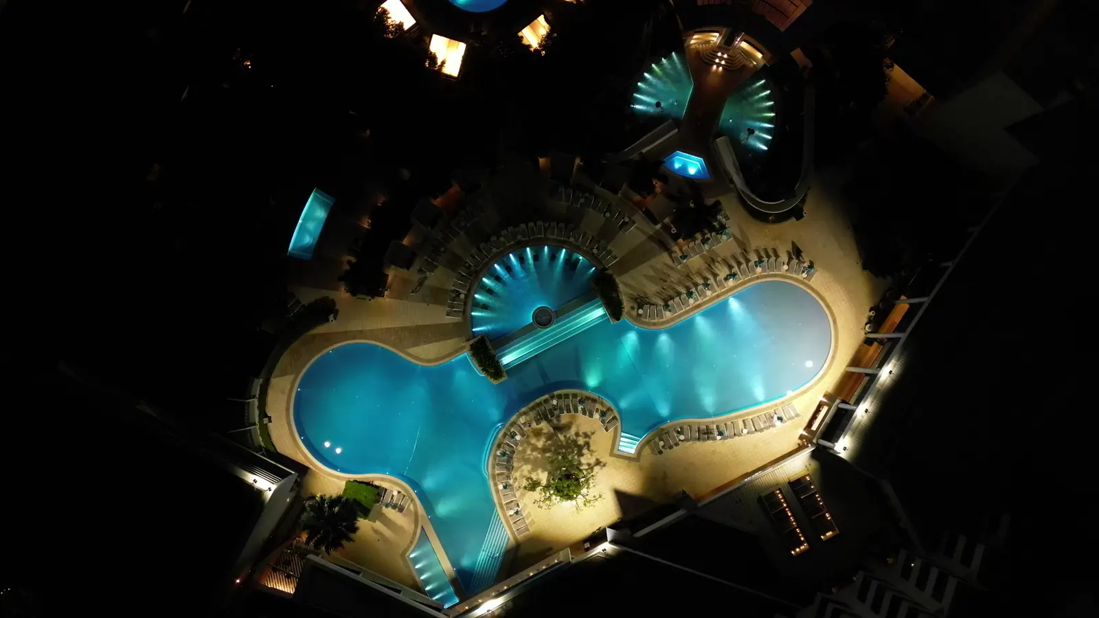 Vista aérea nocturna de una piscina de hotel iluminada