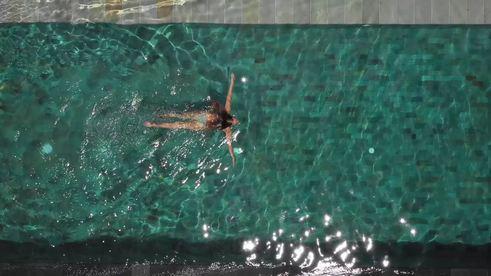 Nadadora en una piscina de andarivel con revestimiento oscuro
